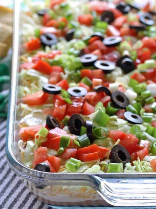 Go big with this 8 layer taco dip recipe - it is the perfect appetizer for large crowds. It's full of meat, cheese, veggies and more! | honeyandbirch.com