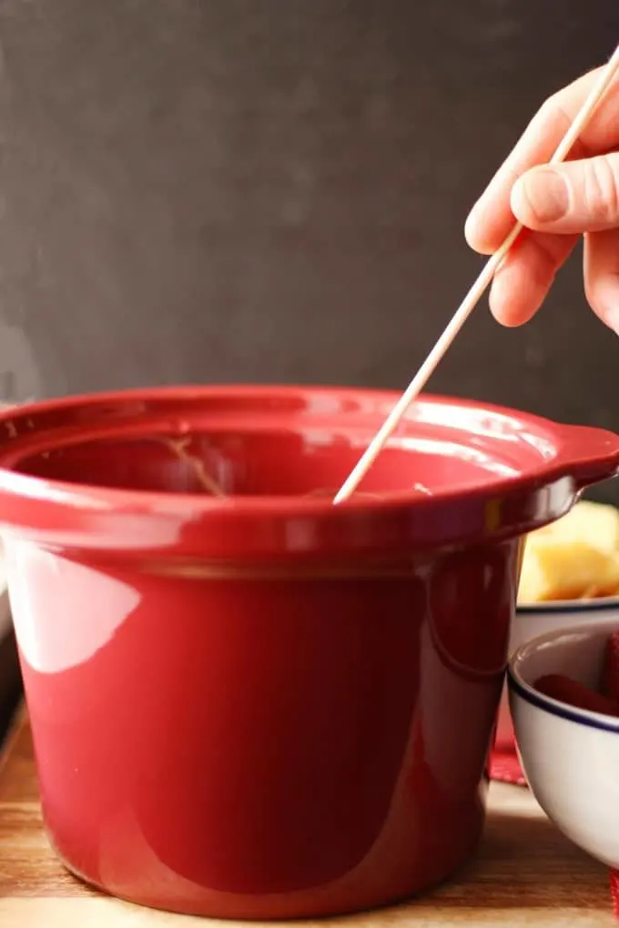 wooden skewer being dipped into chocolate fondue