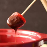 strawberry dipped into slow cooker chocolate fondue