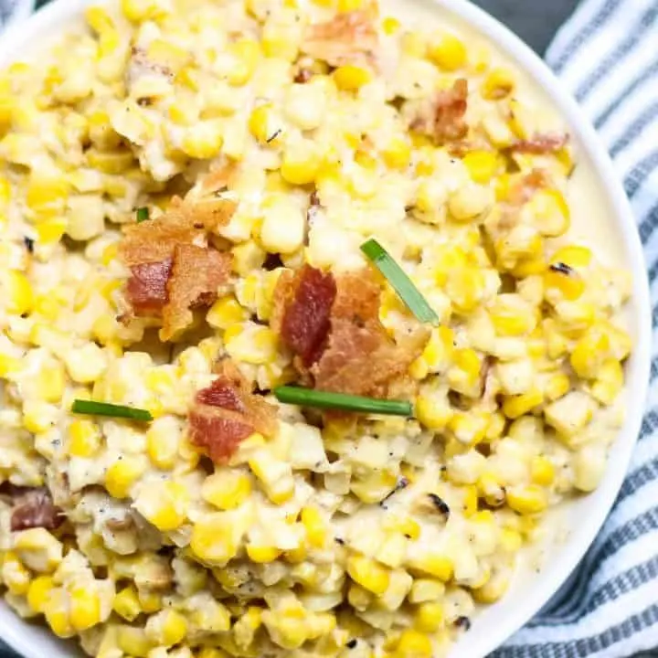 white bowl of creamed corn with a blue napkin