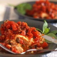 slow cooker bruschetta chicken on a gray plate and a blue and white naplkin