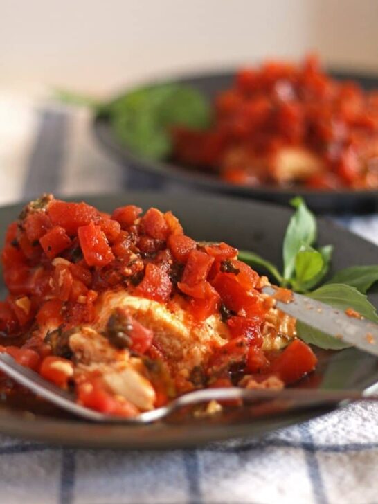 slow cooker bruschetta chicken on a gray plate and a blue and white naplkin