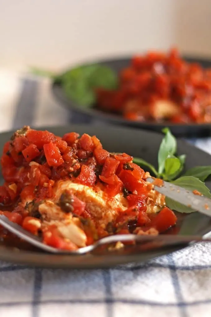 slow cooker bruschetta chicken on a gray plate and a blue and white naplkin