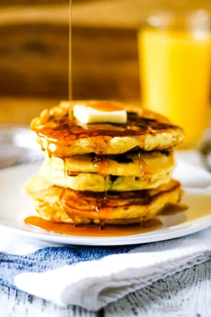 syrup being poured on blueberry orange pancakes