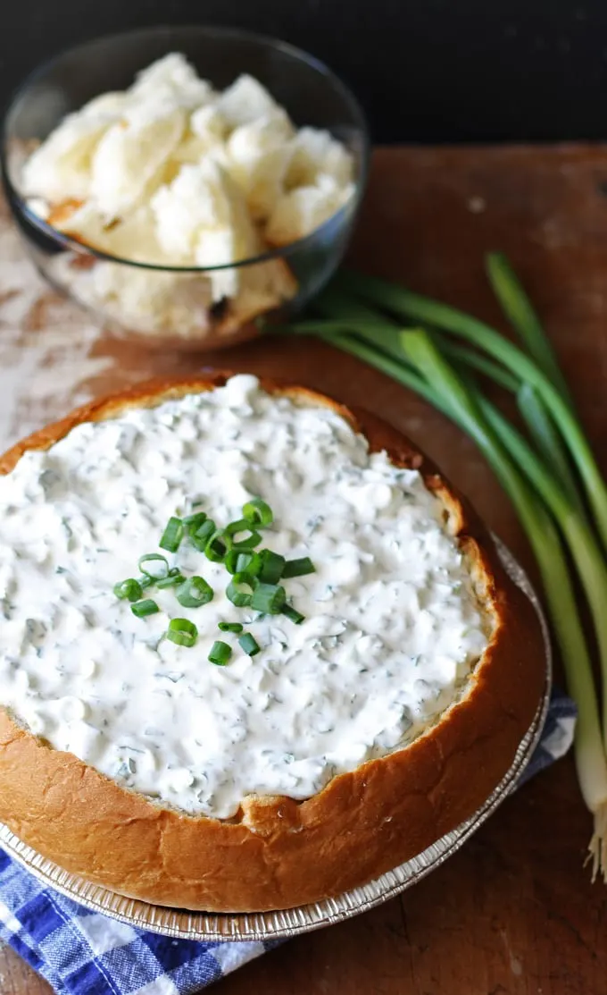 green onion dip in a bread bowl with bread chunks in a second small bowl