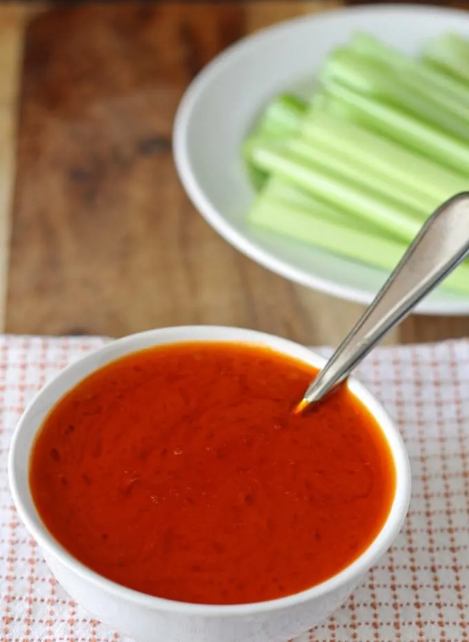 buffalo sauce in a small bowl with celery sticks