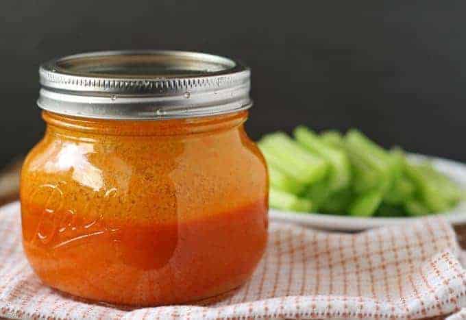 Buffalo sauce in a jar with celery sticks