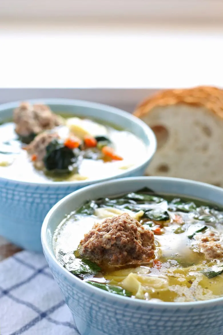 two blue bowls of soup with large meatballs