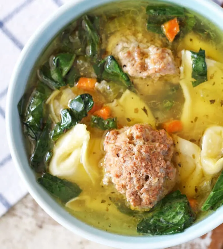 bowl of soup full of tortellini and large meatballs
