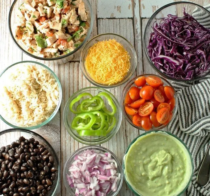 Leftover chicken burrito bowls topped with avocado crema. Full of veggies and flavor, they are the perfect use for leftover chicken! | honeyandbirch.com