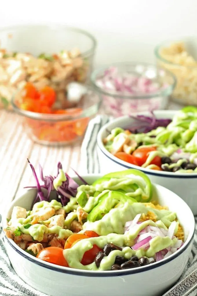 Leftover chicken burrito bowls topped with avocado crema. Full of veggies and flavor, they are the perfect use for leftover chicken! | honeyandbirch.com