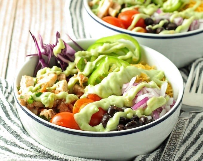 Leftover chicken burrito bowls topped with avocado crema. Full of veggies and flavor, they are the perfect use for leftover chicken! | honeyandbirch.com