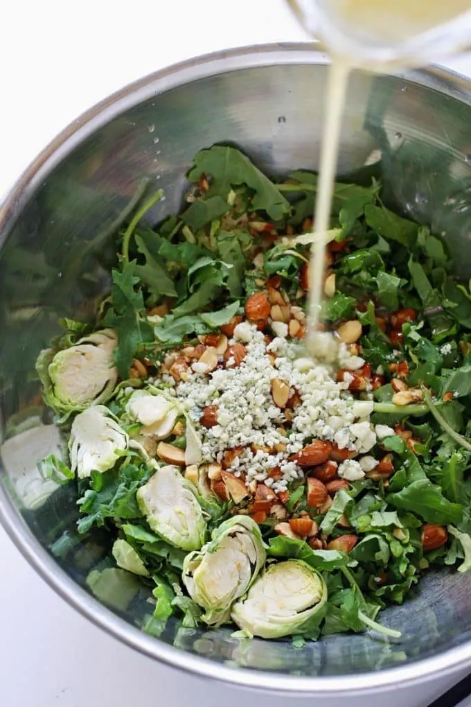 salad dressing poured on Brussels sprouts kale salad