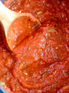 basil roasted garlic tomato sauce in a pot with a wooden spoon