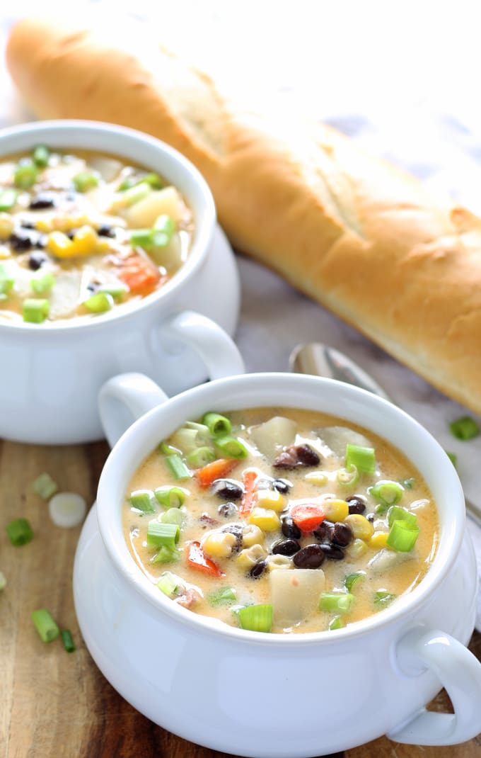two bowls of black bean corn chowder and a loaf of bread