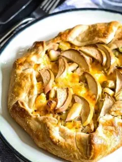 whole savory apple galette on a black and white plate