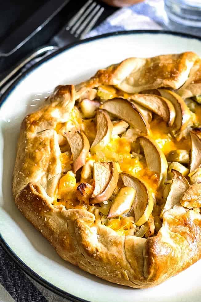 whole savory apple galette on a black and white plate