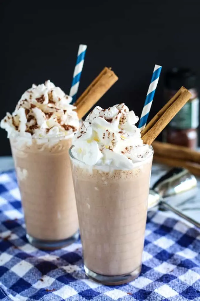 two Mexican chocolate milkshakes garnished with whipped cream and cinnamon sticks
