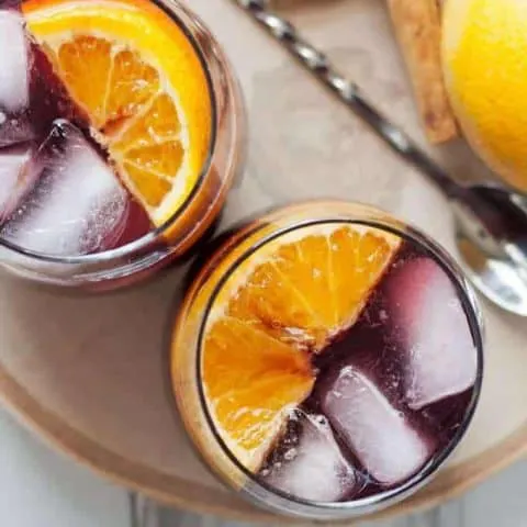 This orange red wine spritzer is a great cocktail for fall and winter. Mix up a batch of cinnamon simple syrup, grab a bottle of your favorite red and try this drink today! | honeyandbirch.com