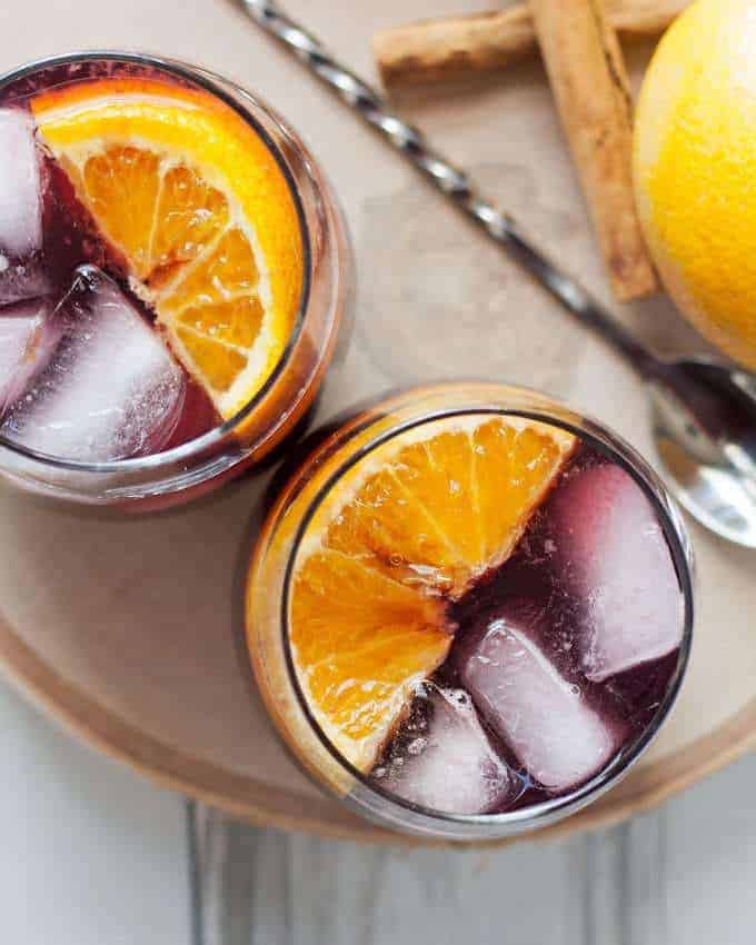 This orange red wine spritzer is a great cocktail for fall and winter. Mix up a batch of cinnamon simple syrup, grab a bottle of your favorite red and try this drink today! | honeyandbirch.com