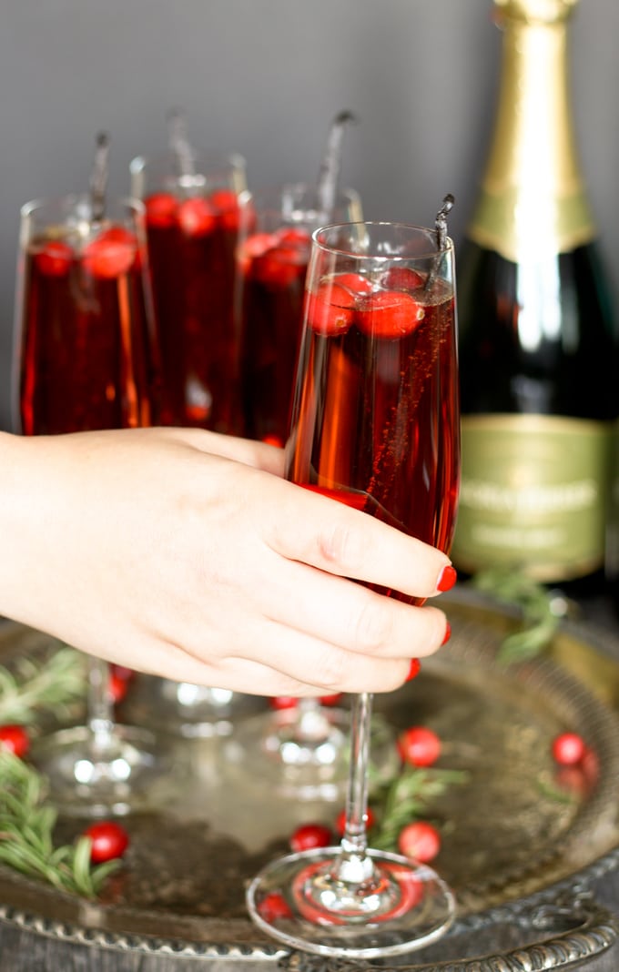 holding a single champagne flute filled with a vanilla cranberry mimosa
