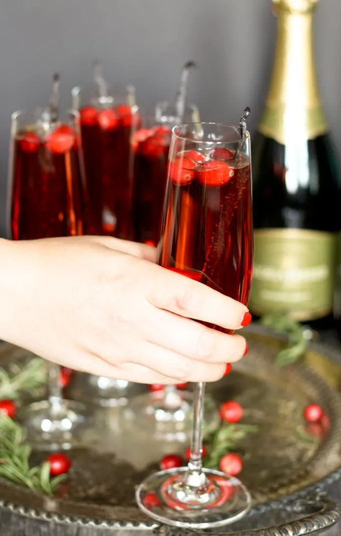 holding a single champagne flute filled with a vanilla cranberry mimosa