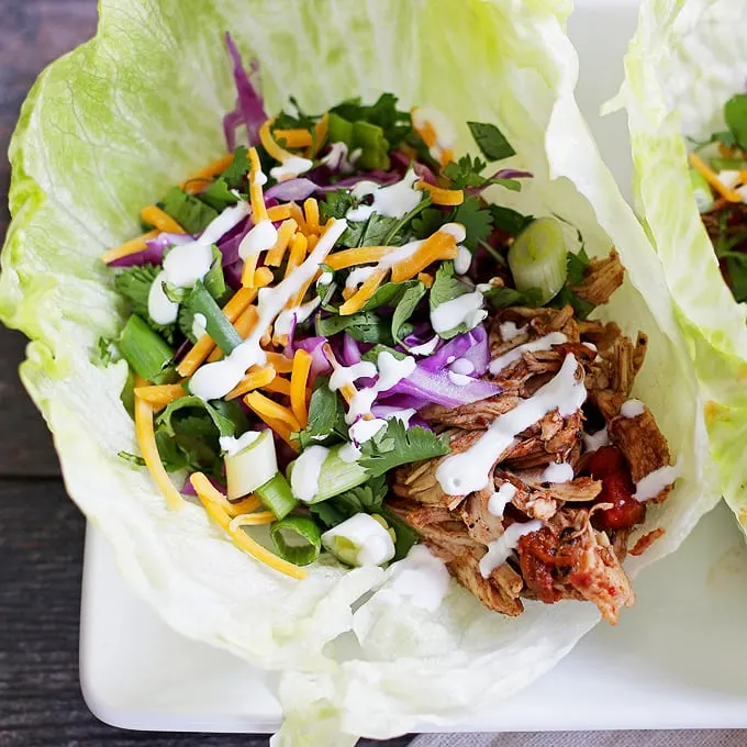 These slow cooker chicken taco lettuce wraps are going to be your new favorite taco recipe. Make the chicken taco meat in the slow cooker and substitute iceberg lettuce leaves for tortilla shells! | honeyandbirch.com