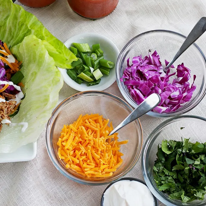 These slow cooker chicken taco lettuce wraps are going to be your new favorite taco recipe. Make the chicken taco meat in the slow cooker and substitute iceberg lettuce leaves for tortilla shells! | honeyandbirch.com