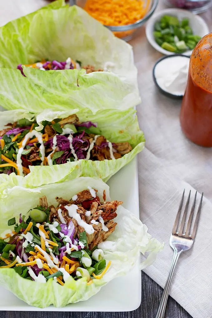 These slow cooker chicken taco lettuce wraps are going to be your new favorite taco recipe. Make the chicken taco meat in the slow cooker and substitute iceberg lettuce leaves for tortilla shells! | honeyandbirch.com