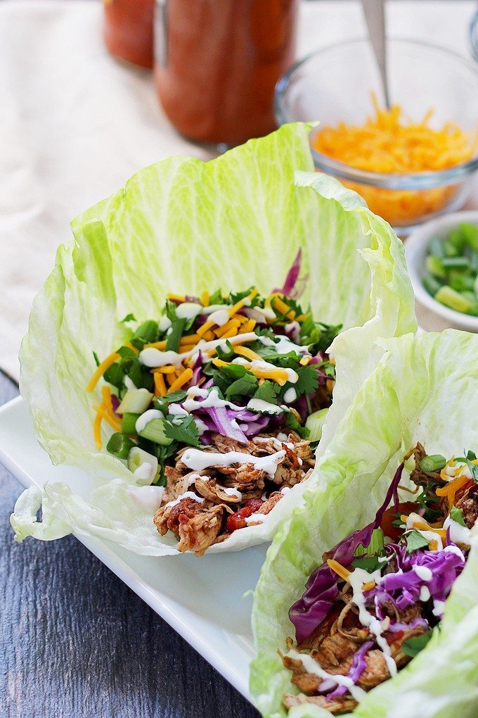 These slow cooker chicken taco lettuce wraps are going to be your new favorite taco recipe. Make the chicken taco meat in the slow cooker and substitute iceberg lettuce leaves for tortilla shells! | honeyandbirch.com