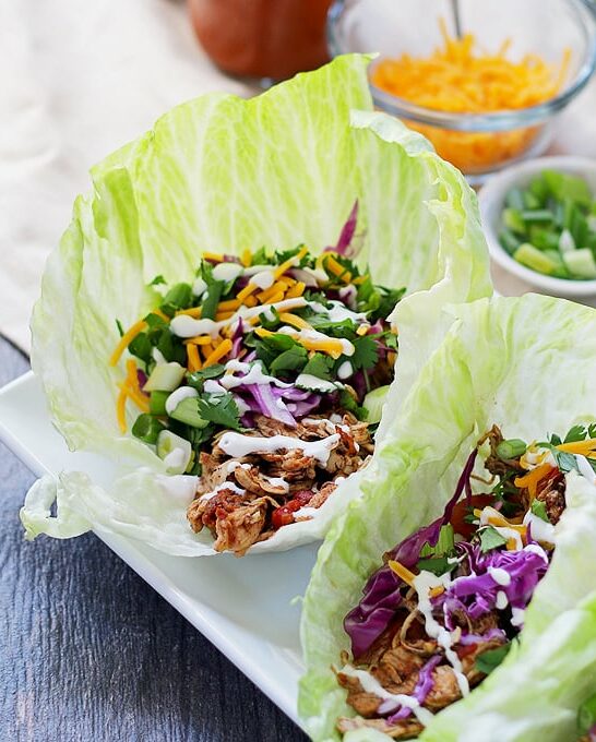 These slow cooker chicken taco lettuce wraps are going to be your new favorite taco recipe. Make the chicken taco meat in the slow cooker and substitute iceberg lettuce leaves for tortilla shells! | honeyandbirch.com