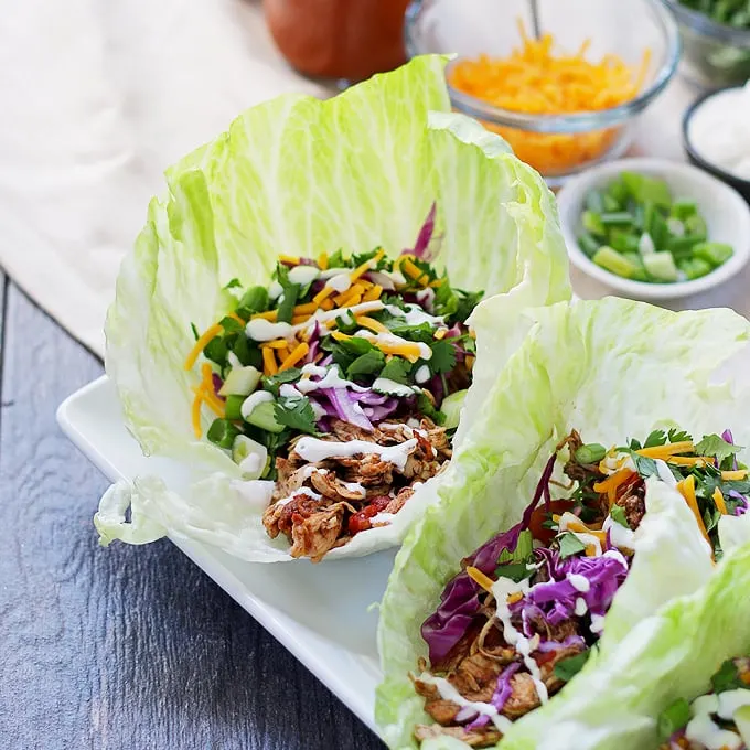 These slow cooker chicken taco lettuce wraps are going to be your new favorite taco recipe. Make the chicken taco meat in the slow cooker and substitute iceberg lettuce leaves for tortilla shells! | honeyandbirch.com