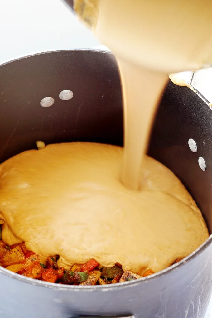chicken fajita mac and cheese with cheese being poured into bowl