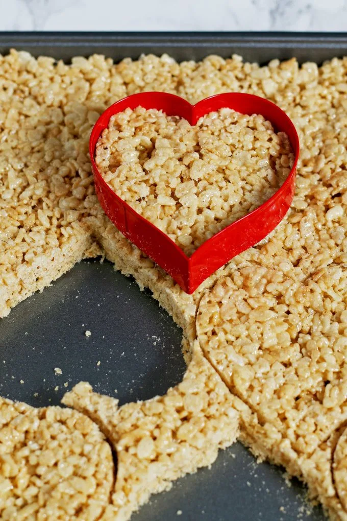 Rice Krispies on a sheet pan with a heart shaped cookie cutter