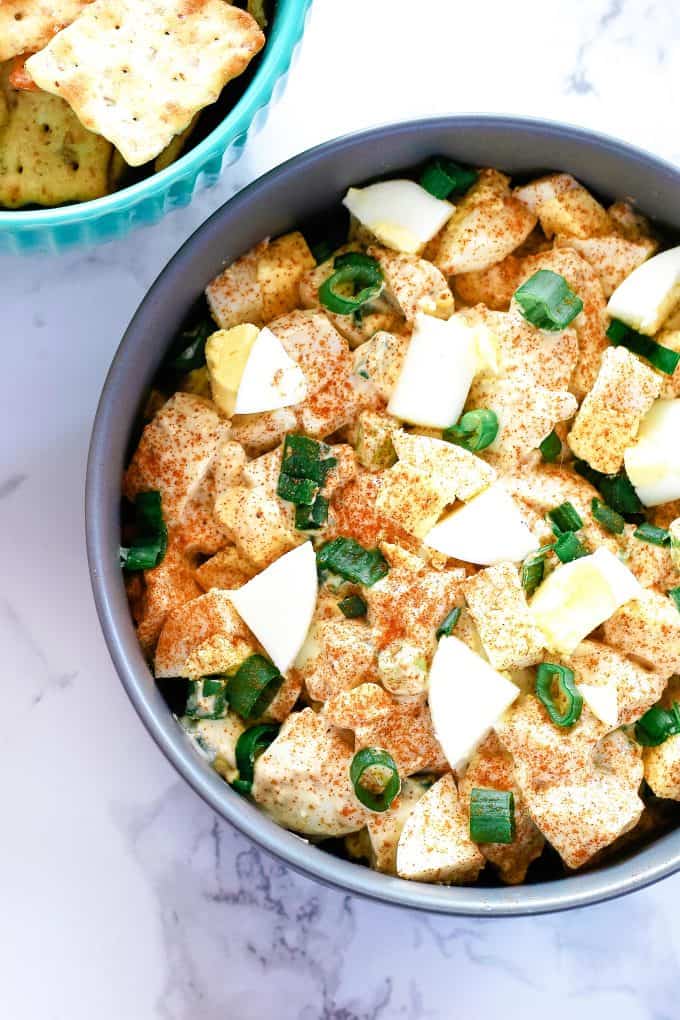 bowl of deviled egg dip and a blue bowl of crackers