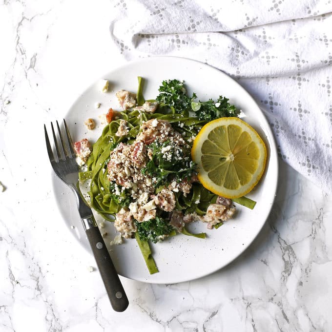 This carbonara-inspired Greek kale pasta is a one-of-a-kind pasta dinner. The flavors of carbonara sauce (bacon!) are combined with elements of Greek cuisine for a savory and delicious dish. | honeyandbirch.com