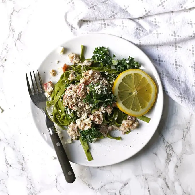 This carbonara-inspired Greek kale pasta is a one-of-a-kind pasta dinner. The flavors of carbonara sauce (bacon!) are combined with elements of Greek cuisine for a savory and delicious dish. | honeyandbirch.com