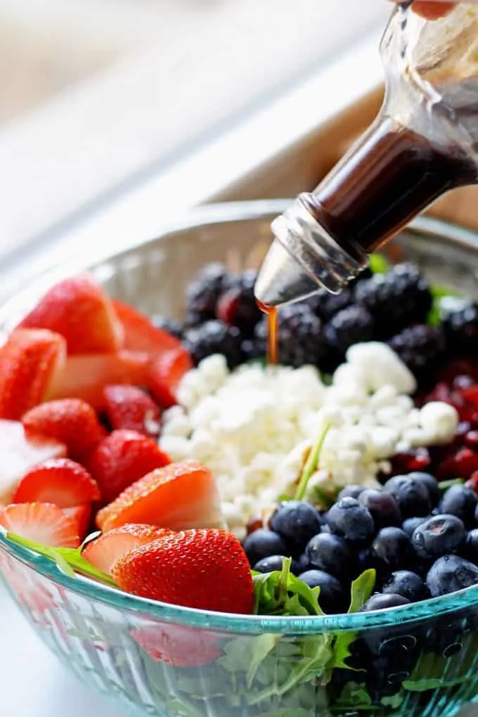 balsamic vinaigrette being poured on berry goat cheese salad