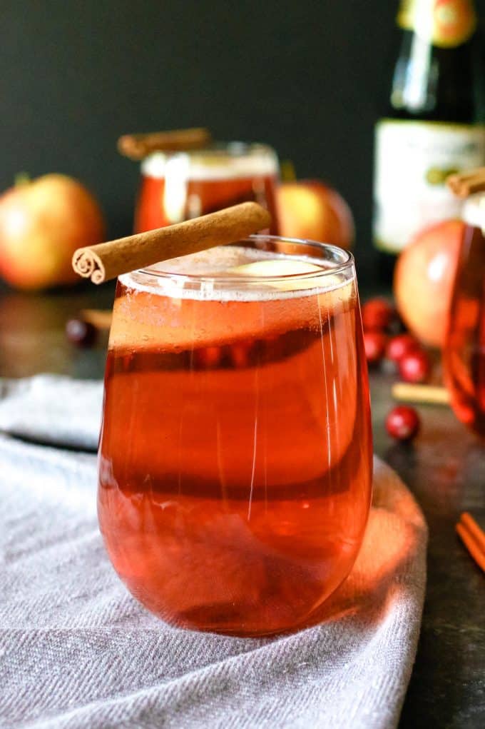 one cranberry apple cider mimosa with a cinnamon stick garnish