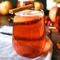 one cranberry apple cider mimosa with a cinnamon stick garnish