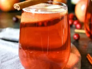 one cranberry apple cider mimosa with a cinnamon stick garnish