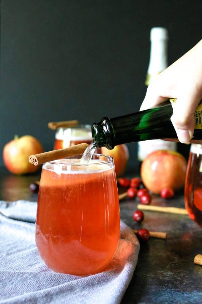 sparkling cider being poured into a cranberry apple cider mimosa