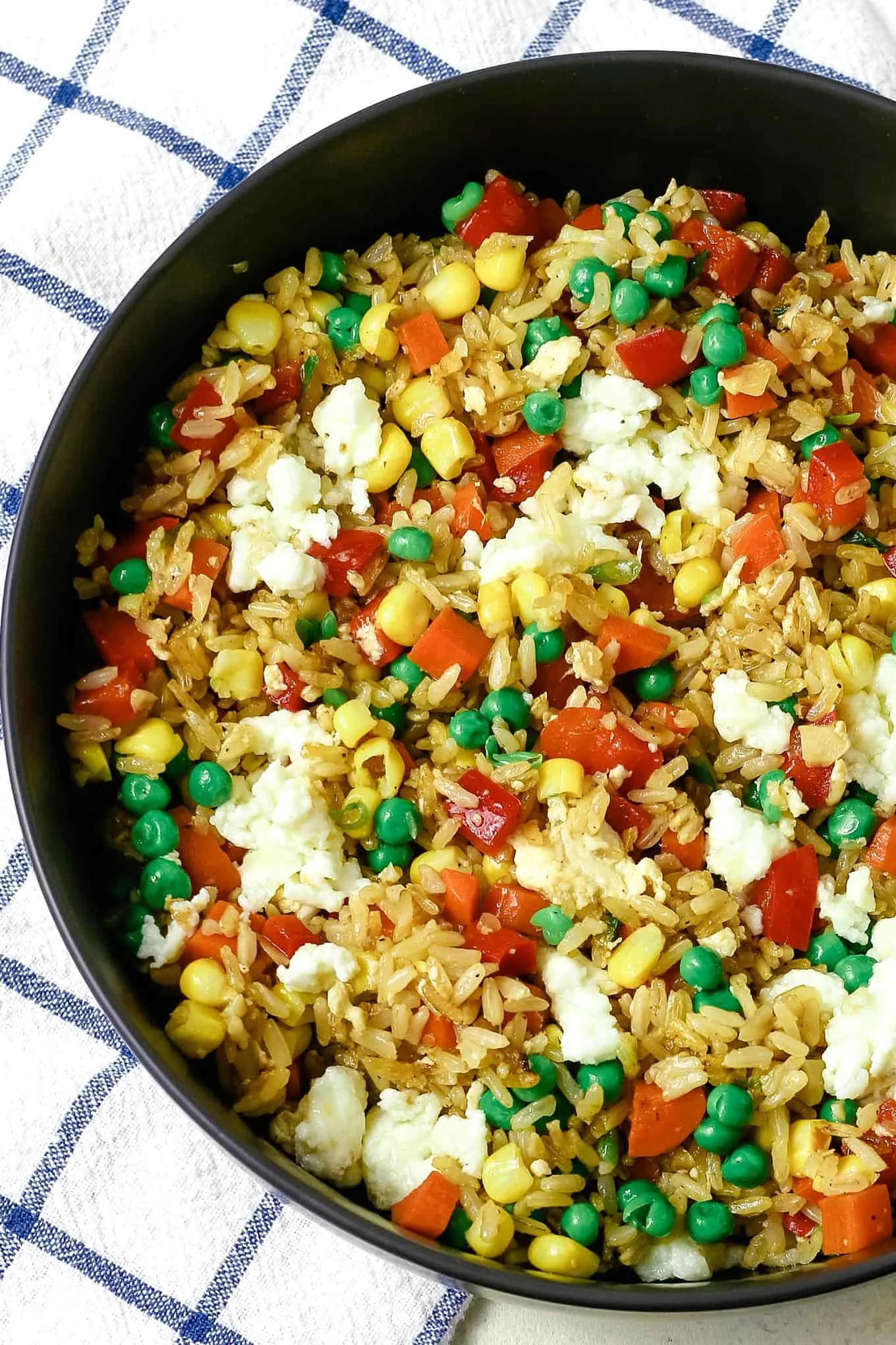 bowl of vegetable fried rice and a blue and white napkin