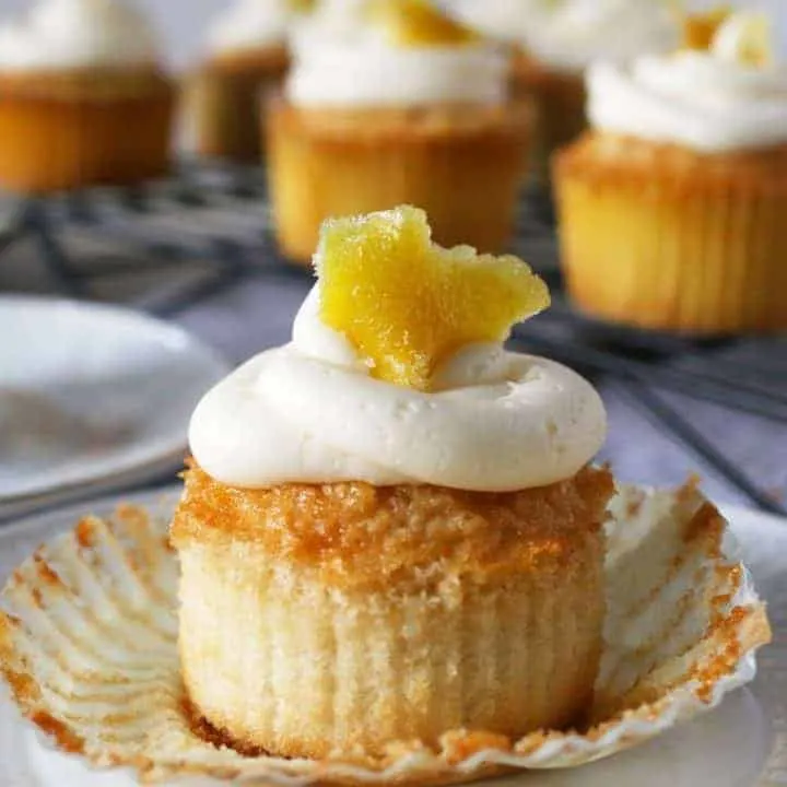 These white cupcakes with lemon frosting are filled with lemon curd and topped with candied lemon peel. They're the perfect sweet treat! This homemade cupcake recipe is easy to make and you can't go wrong with a filled cupcake topped with a fancy decoration!