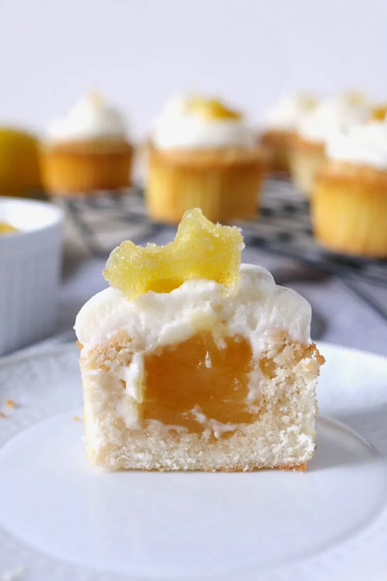 These white cupcakes with lemon frosting are filled with lemon curd and topped with candied lemon peel. They're the perfect sweet treat! This homemade cupcake recipe is easy to make and you can't go wrong with a filled cupcake topped with a fancy decoration!