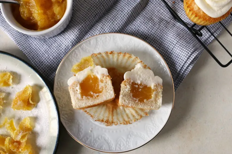 These white cupcakes with lemon frosting are filled with lemon curd and topped with candied lemon peel. They're the perfect sweet treat! This homemade cupcake recipe is easy to make and you can't go wrong with a filled cupcake topped with a fancy decoration!