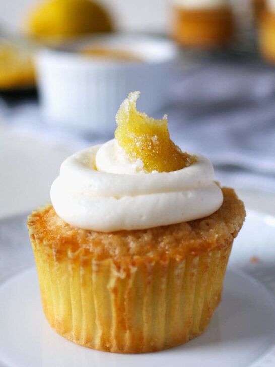 These white cupcakes with lemon frosting are filled with lemon curd and topped with candied lemon peel. They're the perfect sweet treat! This homemade cupcake recipe is easy to make and you can't go wrong with a filled cupcake topped with a fancy decoration!