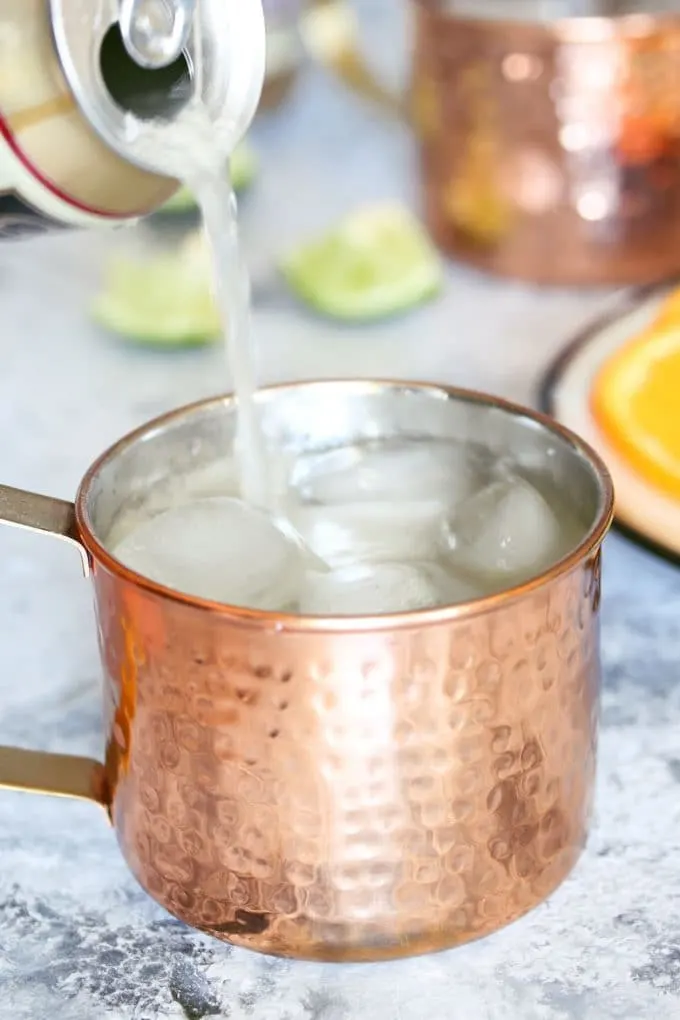 pouring ginger beer into a mule cocktail