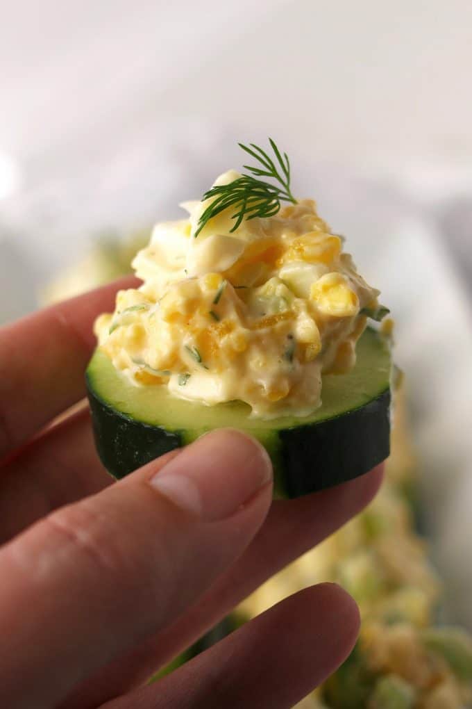 hand holding an egg salad cucumber canapé