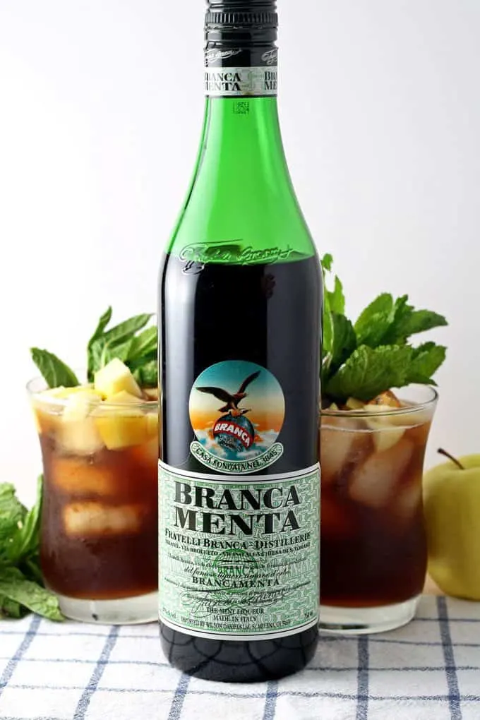 bottle of branca menta with two apple mint iced tea cocktails